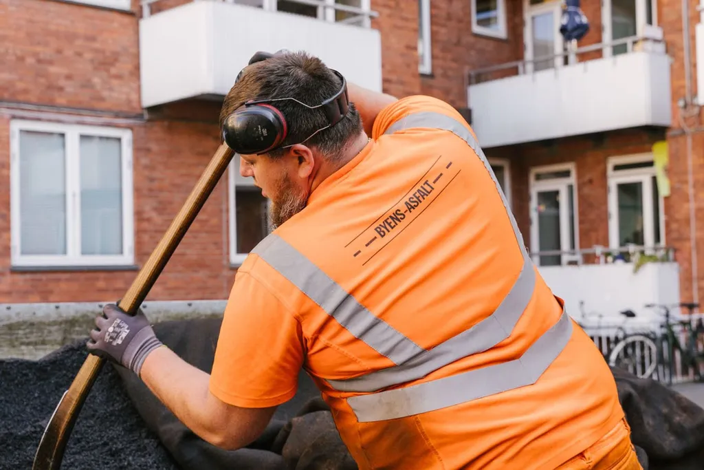 Medarbejder skovler varm asfalt